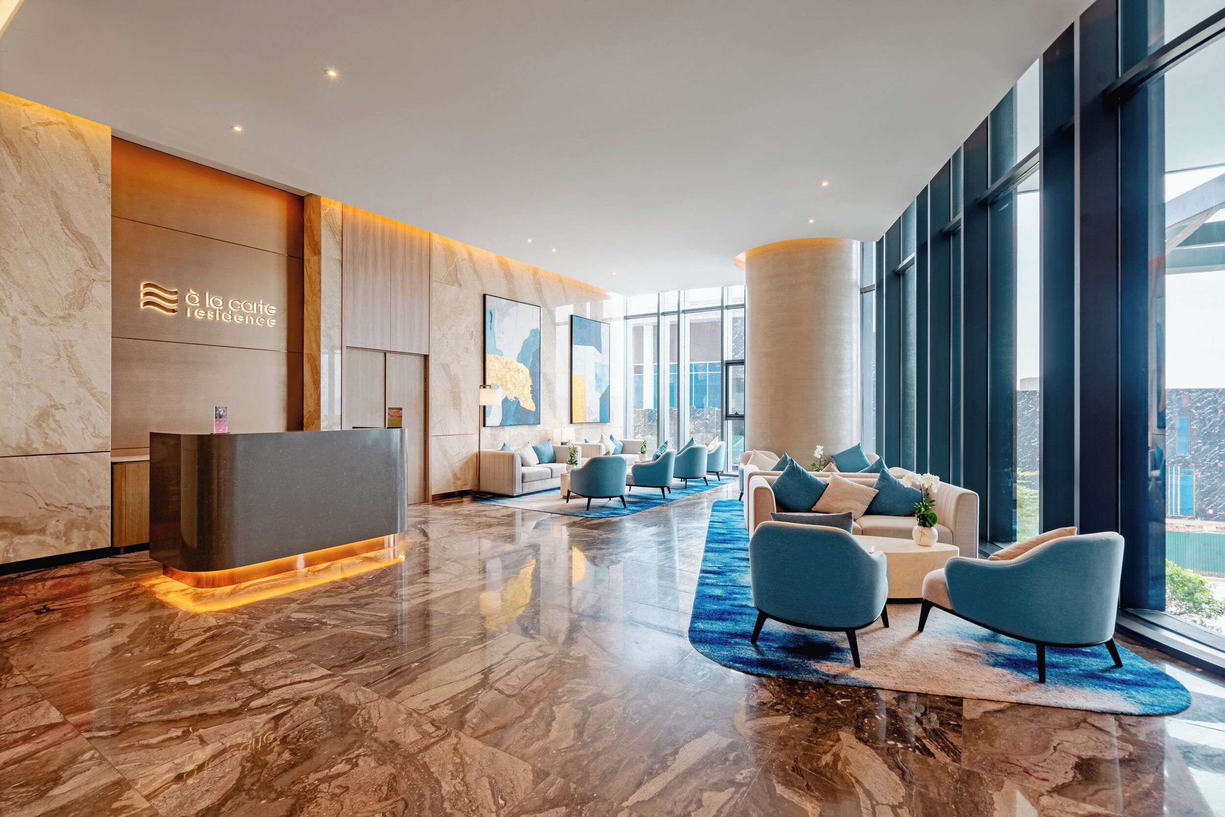 A modern hotel lobby with a reception desk, seating area, and large windows offering views.