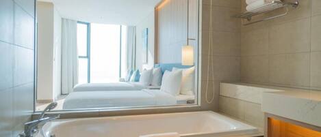 A modern hotel bathroom with a large bathtub, a mirror, and a towel rack.