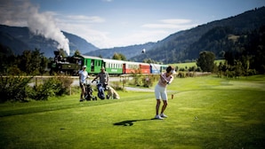 A golf course with a train in the background.