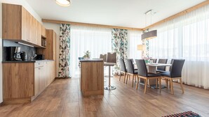 Eine moderne Küche mit Holzausstattung, einer zentralen Kochinsel und einem Essbereich mit Tisch und Stühlen.