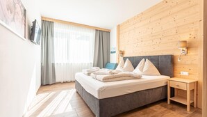 Ein modernes Schlafzimmer mit grauem Bett, einer Wand aus Holzpaneelen und einem kleinen Nachttisch mit Lampe.