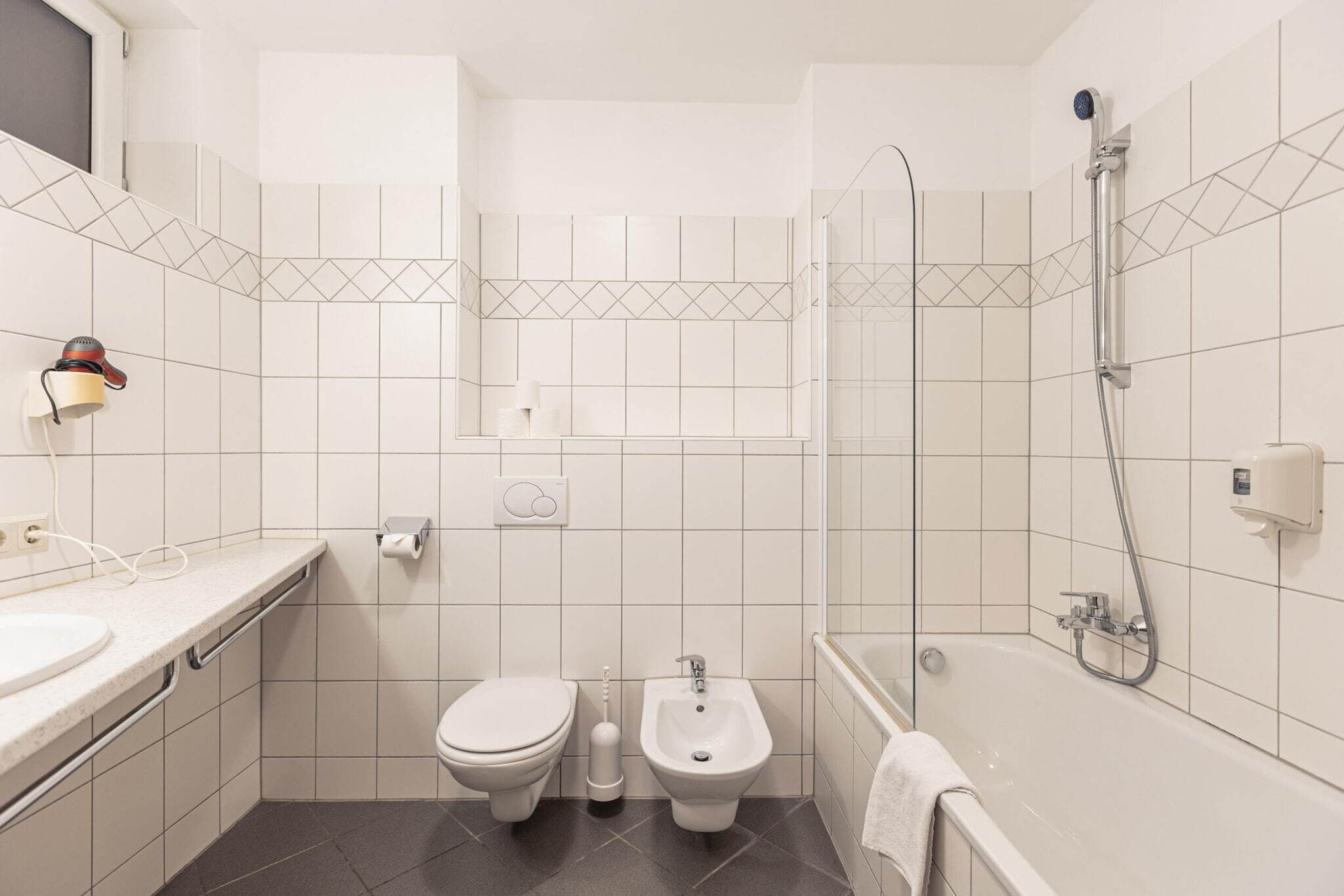 A compact bathroom with a toilet, bidet, and shower.