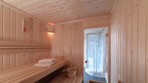 A sauna room with wooden benches, a wooden bucket, and a glass door leading to a shower area. - Holiday Home in Zeeland near the Sea (Colijnsplaat)