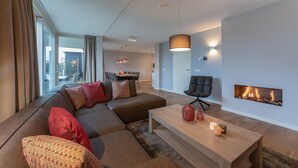 A modern living room with a sectional sofa, a coffee table, and a fireplace. - Holiday Home in Zeeland near the Sea (Colijnsplaat)