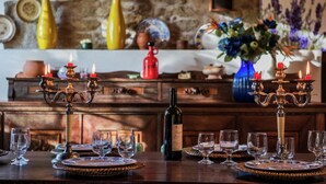 Mesa de jantar posta com taças de vinho, uma garrafa de vinho e candelabros.