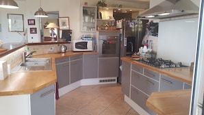 Eine moderne Küche mit grauen Schränken, einer Holz Arbeitsplatte, einem Gasherd, einer Mikrowelle und einem Kühlschrank.