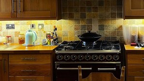 Een keuken met houten kastjes, een gasfornuis en een afzuigkap.