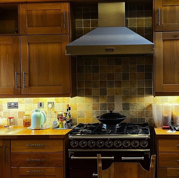 A kitchen with wooden cabinets, a gas stove, and a range hood.