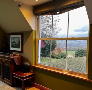 A room with a large window, a framed picture on the wall, and a small table with a globe.