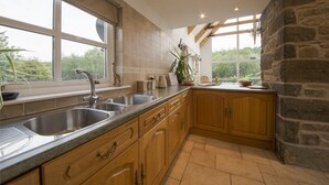 A kitchen with a large window, stone wall, and wooden cabinets. - Exceptionally spacious 5 star holiday home with 4 bedrooms, large living room, dining kitchen, log f (Aberfeldy)