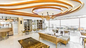 A modern interior with a high ceiling, circular wooden patterns, and a dining area with wicker furniture.