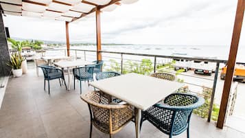An outdoor patio with tables and chairs, overlooking a body of water with boats.