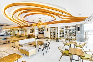 A modern cafe with a central seating area, wooden ceiling design, and a view of the city. - Hotel Dulcee (Naga City)
