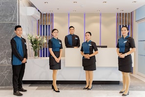 A reception area with a marble reception desk, a plant, and a modern ceiling design. - Hotel Dulcee (Naga City)