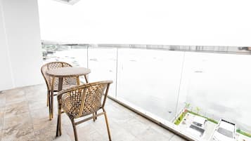 A balcony with wicker chairs and a view of a body of water.