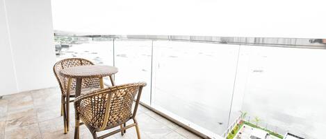 A balcony with wicker chairs and a view of a body of water.