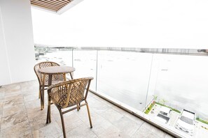 A balcony with wicker chairs and a view of a body of water. - Hotel Dulcee (Naga City)