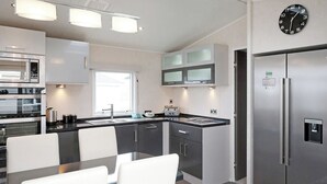 Une cuisine moderne équipée d’un four, d’un micro-ondes et d’un réfrigérateur intégrés. Elle comprend également un coin repas avec une table et des chaises.