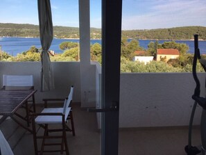 Enjoy the serene view of the water from this balcony, featuring a table and chairs, perfect for relaxation and exercise.