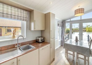 A kitchen with a sink, a toaster, and a window overlooking a house. - 2 bedroom accommodation in Swinethorpe, Nr Lincoln (Swinethorpe, Nr Lincoln)