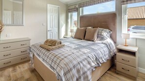 A bedroom with a bed, bedside tables, a dresser, a mirror, and a window with blinds. - 2 bedroom accommodation in Swinethorpe, Nr Lincoln (Swinethorpe, Nr Lincoln)