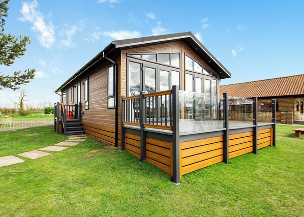 A modern wooden cabin with large windows, a deck, and a staircase leading to the entrance. - 2 bedroom accommodation in Swinethorpe, Nr Lincoln (Swinethorpe, Nr Lincoln)