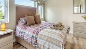 A bedroom with a bed, bedside table, dresser, and a window with curtains. - 1 bedroom accommodation in Swinethorpe, Nr Lincoln (Swinethorpe, Nr Lincoln)