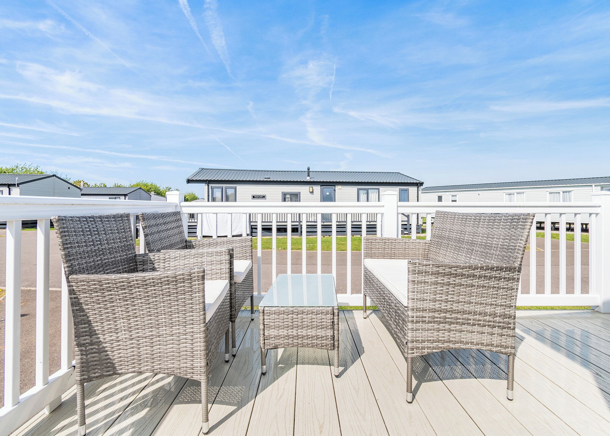 A deck with wicker furniture and a view of a building in the background.
