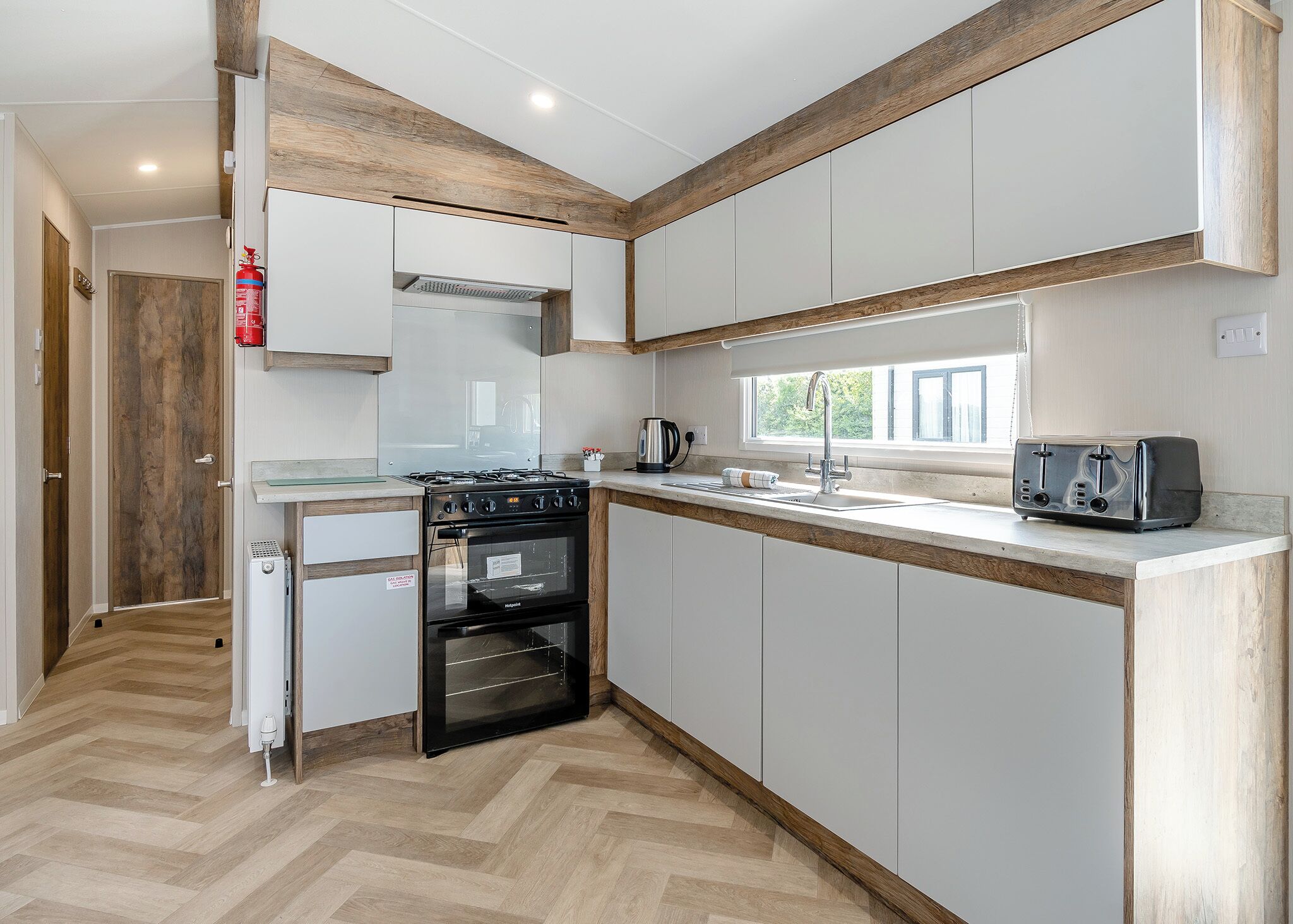 A compact kitchen with white cabinets, a black stove, and a toaster.