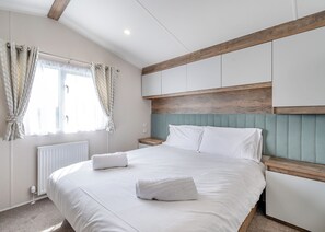 Ein Schlafzimmer mit Bett, weißen Vorhängen, einem Holz-Kopfteil und einer Heizung.