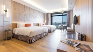 A modern hotel room with two beds, a small table, a TV, and a balcony with a view.