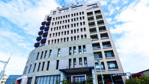 A modern hotel with a prominent entrance, multiple floors, and a clear sky.