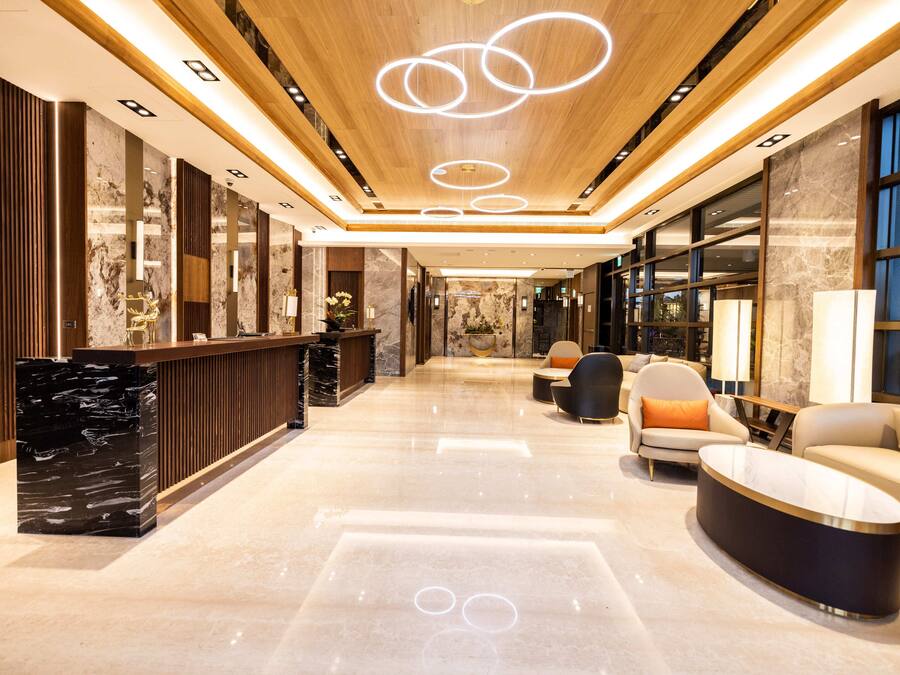 Una hall moderna con una reception in marmo, un'area salotto e un soffitto con lampade circolari.
