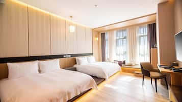 Habitación de hotel con dos camas, un escritorio, una silla y un televisor.