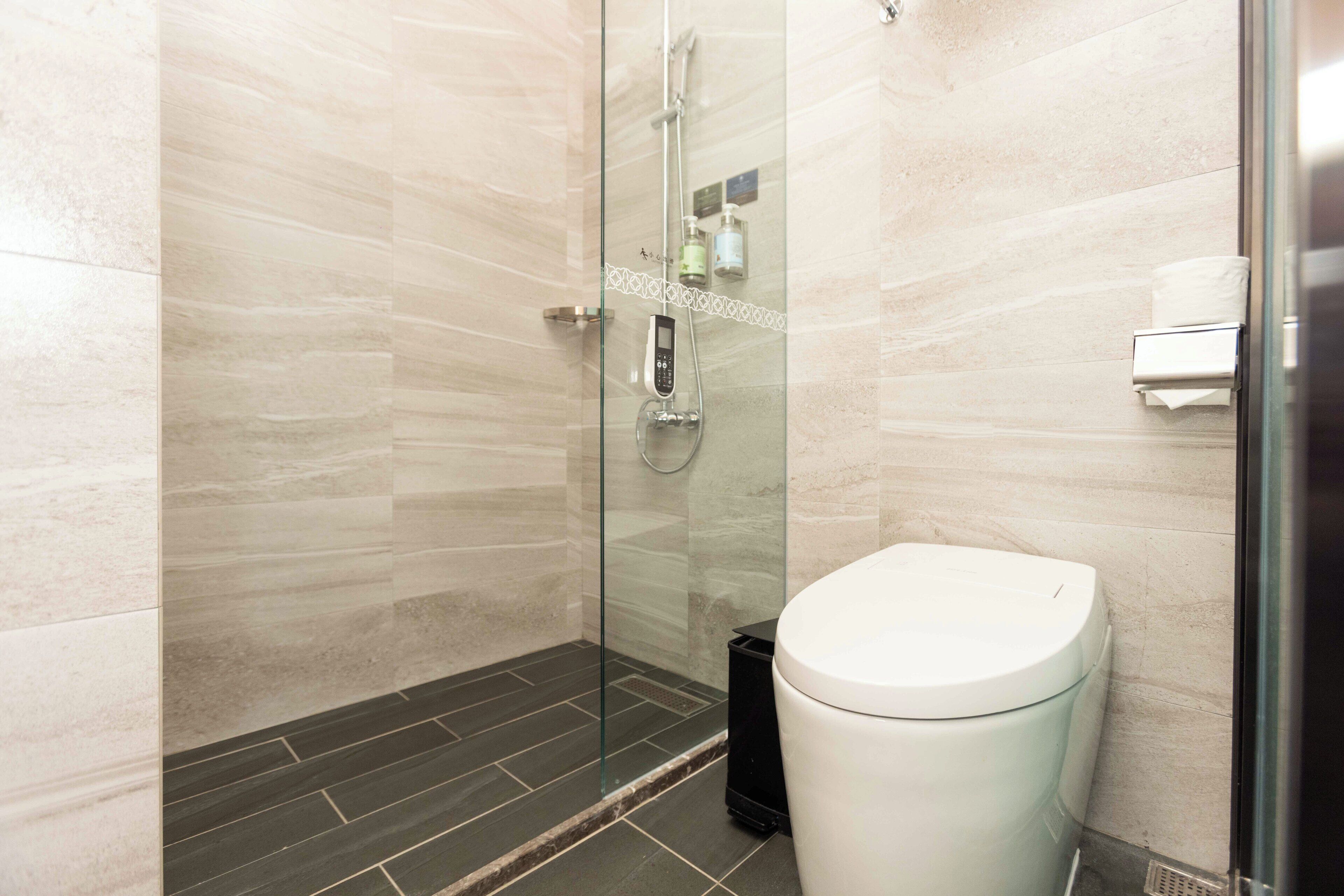 A modern bathroom with a glass-enclosed shower, a white toilet, and a tiled floor.
