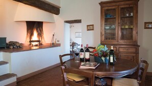 A dining area with a wooden table, chairs, a fireplace, and a cabinet with glass doors.