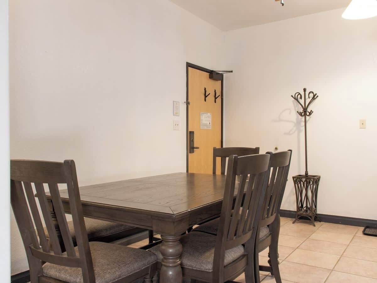 Ein Esszimmer mit Holztisch, vier Stühlen, einem Garderobenschrank und einer Tür mit einem Schild.