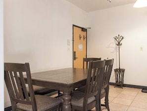 A dining room with a wooden table and four chairs, a coat rack, and a door with a sign. - 7 Guests 2BR 2BA, Pool, Hot Tub & Game Room at CBL (Brian Head)