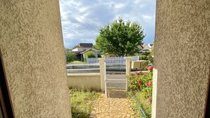 Una entrada empaveda de piedra con cerca blanca de piquetes y un árbol al fondo.