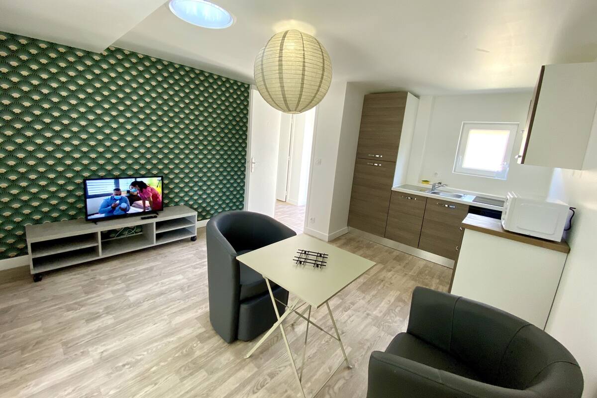 Una sala moderna con televisor, una mesa de comedor y una zona de cocina.