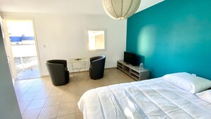 Un dormitorio con cama, televisión, ventana y balcón.