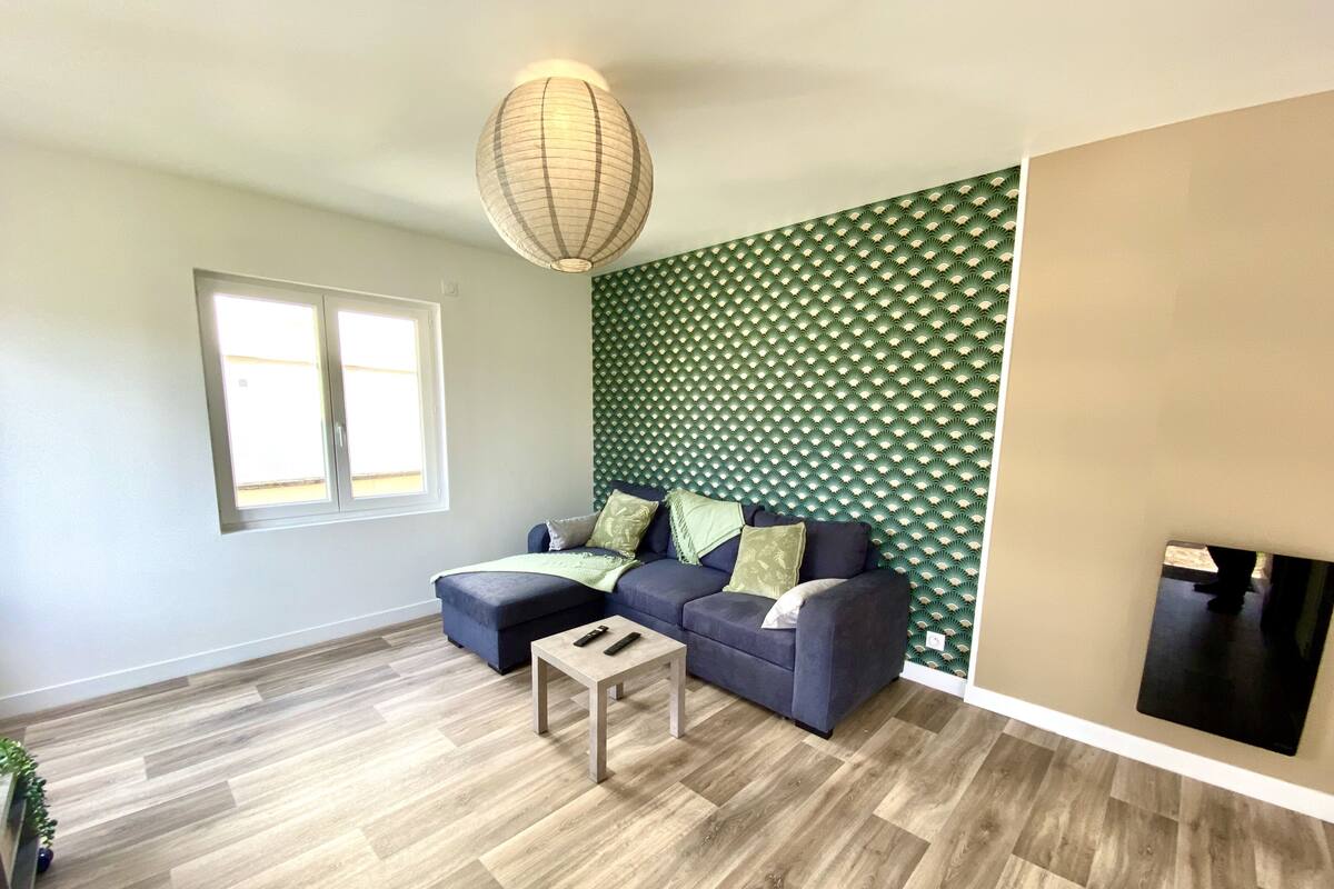 Una sala de estar moderna con un sofá seccional, una mesita de centro y una lámpara colgante decorativa.