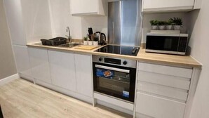Una cucina moderna con mobili bianchi, una cappa aspirante in acciaio inossidabile, un forno a microonde e un forno.