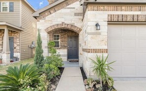 Une maison d’habitation avec une façade en pierre, une porte d’entrée et un garage.