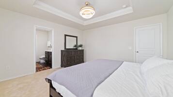 A bedroom with a bed, dresser, mirror, and a door.