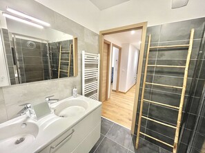 Een moderne badkamer met een grote spiegel, een badkuip en een wastafelmeubel met een wastafel.