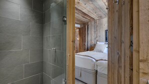 A modern bathroom with a glass shower enclosure and a wooden ceiling. - Luxury Apartment with Hammam, Fireplace, and Mountain View in Val d'Isère (Val-d'Isère)