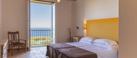 Una camera da letto con un letto, una sedia, un comodino e vista sull'esterno.