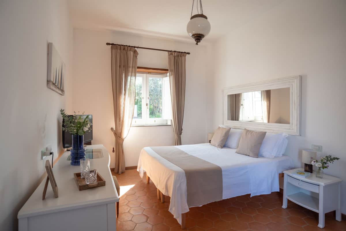 Une chambre à coucher avec un lit, une table de chevet et une fenêtre avec des rideaux.