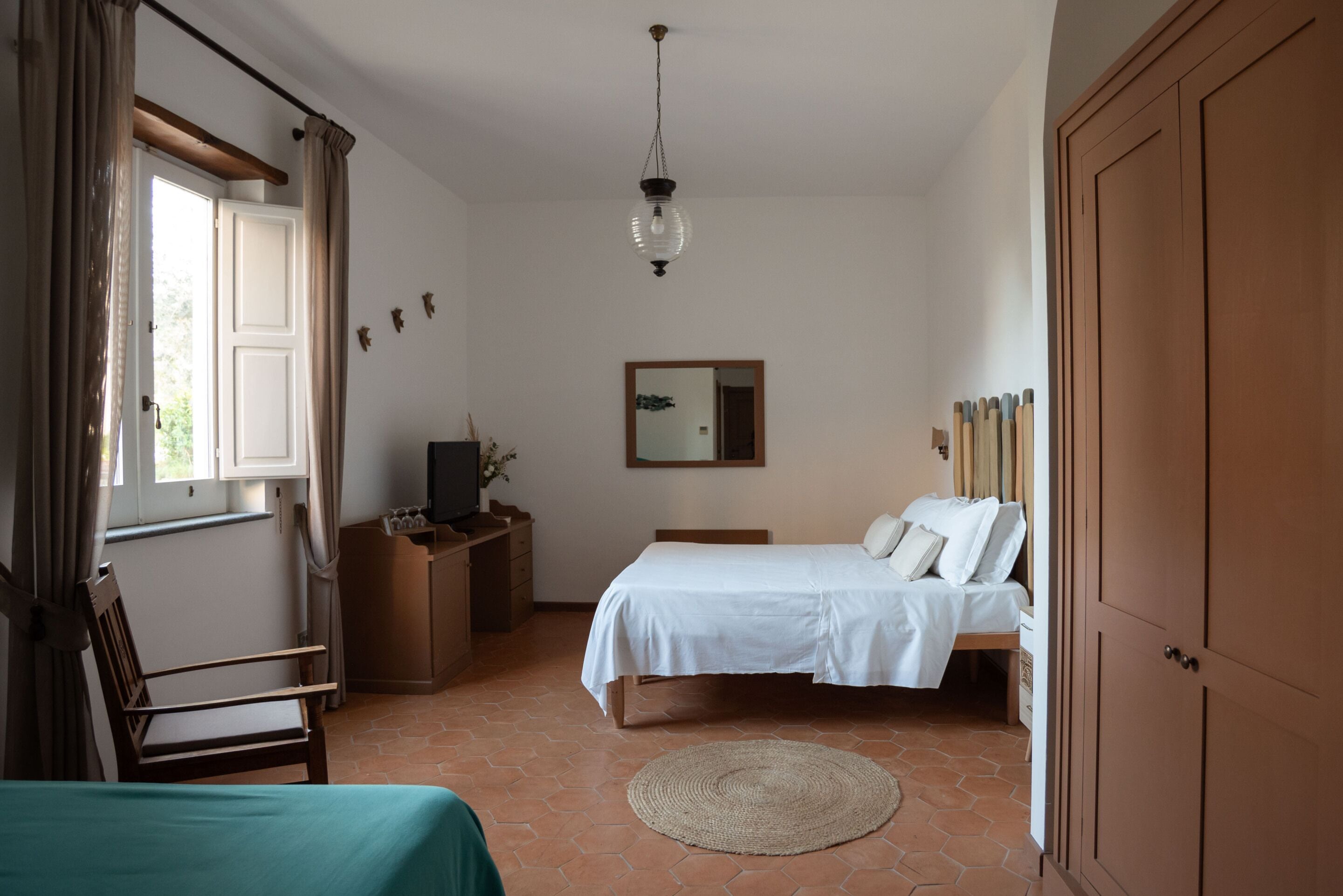 Un dormitorio con cama, escritorio, silla, televisor y espejo.